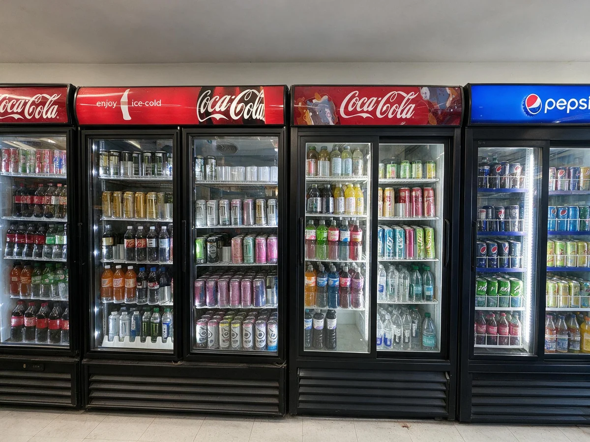 Cooler wall stocked with Coca-Cola, Pepsi and bottled drinks